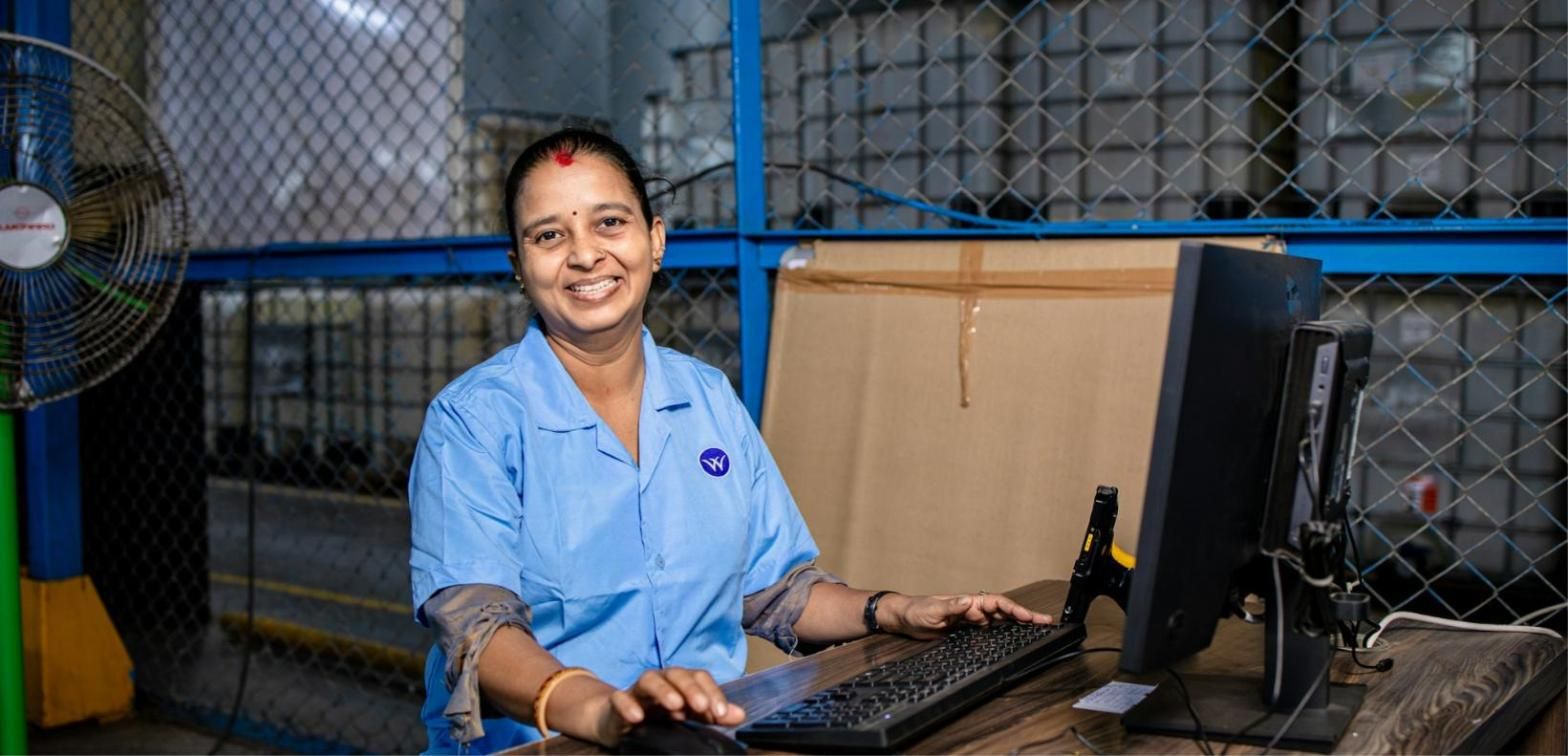 Trabajadora sonriendo ante su puesto de trabajo en un almacén